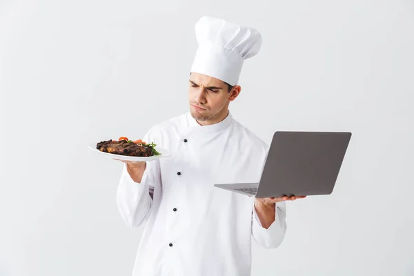 Cozinheiro Chef Sério Vestindo Uniforme Sobre Fundo Branco Segurando Computador — Fotografia de Stock