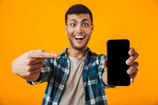 愉快的年轻人穿着格子衬衫站在橙色背景孤立 显示空白屏幕手机 — 图库照片
