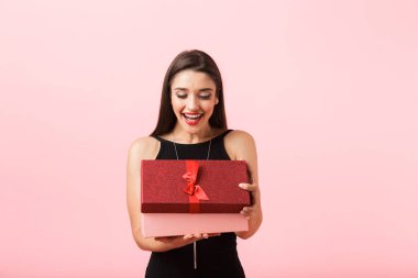 Siyah giyen güzel bir genç kadının portresi pembe arka plan üzerinde izole ayakta elbise, hediye kutusu açın