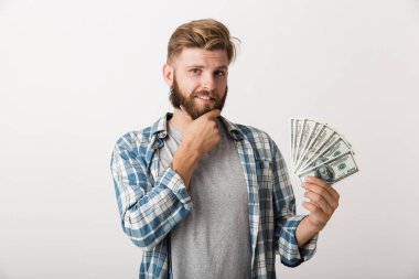 Yakışıklı bir genç sakallı adam para tutan beyaz duvar arka plan üzerinde izole ayakta görüntüsünü.