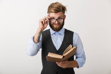 Yakışıklı bir genç sakallı adam kitap okuma holding beyaz duvar arka plan üzerinde izole ayakta görüntüsünü.