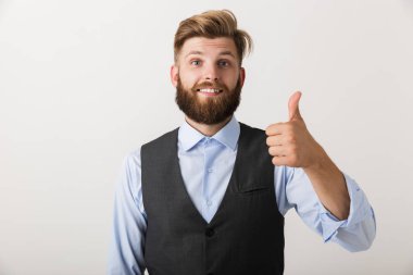 Başparmak yukarıya jest yapmak imge-in mutlu bir genç sakallı adam beyaz duvar arka plan üzerinde izole ayakta.