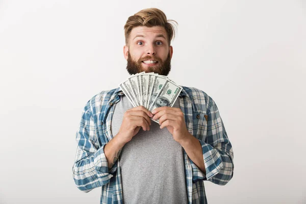 一个英俊的年轻胡须男子站在白色的墙壁背景举行金钱的图像 — 图库照片