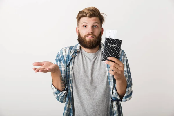 一个英俊的年轻胡须男子站在白色墙壁背景拿着护照的图片 — 图库照片