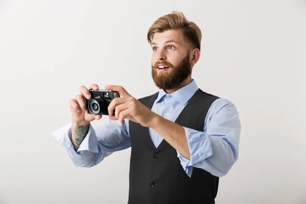 照片中 一位英俊的年轻胡须男子摄影师站在白色墙壁背景上 拿着相机 — 图库照片