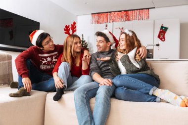 Süre dairede yeni yıl kutlama oturma odasında kanepede oturan çok ırklı insanlar gülümsüyor, Grup