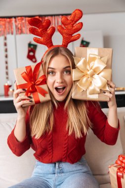 Sürpriz kız 20'li yaşlarda portresi süre kutlama Noel hediye kutuları ile oturma odasında kanepede oturan