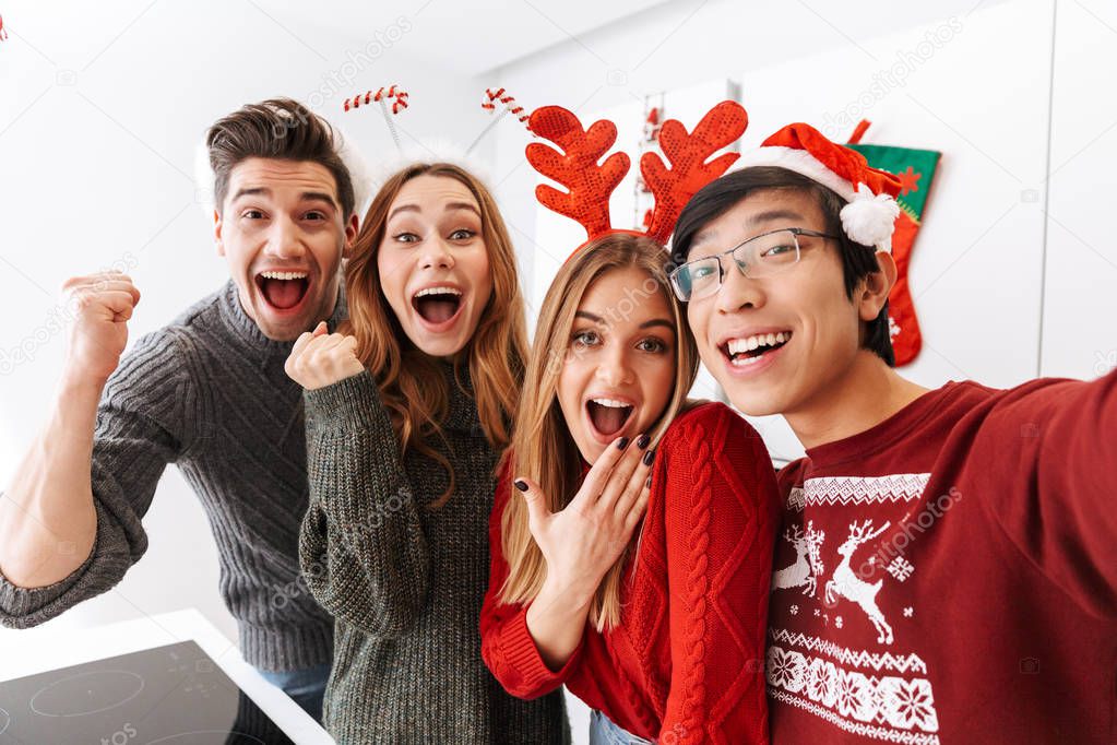 Group of excited multiethnic people celebrating New Year and taking selfie photo together