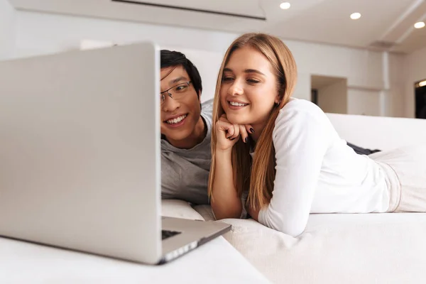 愉快的夫妇的形象 夫妻们一起躺在家里的床上 拿着银笔记本电脑 — 图库照片