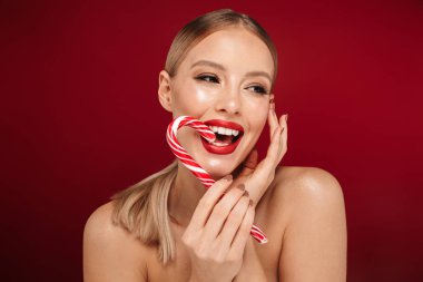 Noel candy yeme kırmızı arka plan üzerinde izole duran bir çekici sarışın saçlı üstsüz kadın güzellik portresi