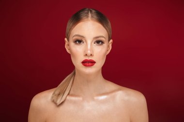 İzole kırmızı arka plan üzerinde duran, poz, kameraya bakarak bir çekici sarışın saçlı üstsüz kadın güzellik portresi