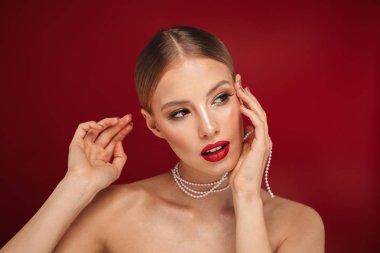 Takı ile poz izole kırmızı arka plan üzerinde duran bir çekici sarışın saçlı üstsüz kadın güzellik portresi