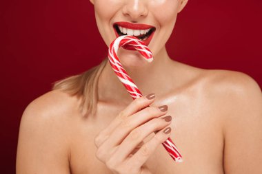 Noel candy koni yeme kırmızı arka plan üzerinde izole duran bir genç ve güzel üstsüz kadın portresi kapatın
