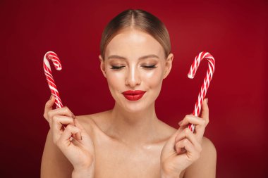 Genç ve güzel bir üstsüz kadın makyaj Güzellik Portresi Noel candy koni holding, kırmızı arka plan üzerinde izole