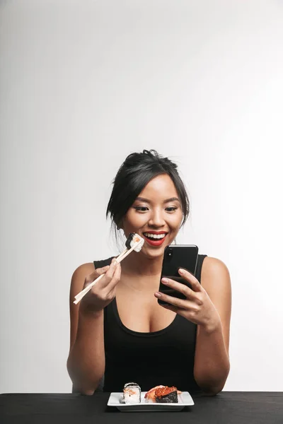 Lachende Jonge Aziatische Vrouw Sushi Eten Aan Tafel Witte Achtergrond — Stockfoto