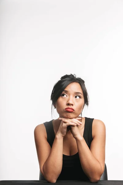 Pensivo Jovem Mulher Asiática Sentado Mesa Isolado Sobre Fundo Branco — Fotografia de Stock