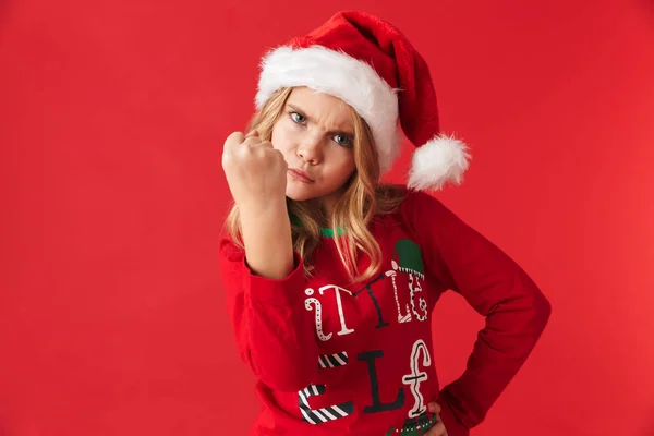 Enojada Niña Usando Sombrero Navidad Pie Aislado Sobre Fondo Rojo — Foto de Stock