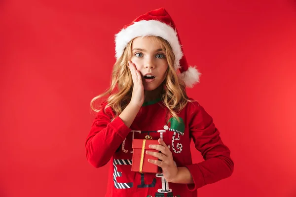 Noel Şapka Ayakta Giyen Sevimli Küçük Kız Kırmızı Arka Plan — Stok fotoğraf