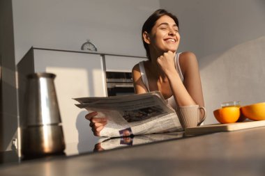 Sabah mutfakta ayakta, gazete okuma, çay içme gülümseyen genç kız