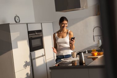 Sabah mutfakta ayakta, kahve fincan, cep telefonuyla pretty genç kız