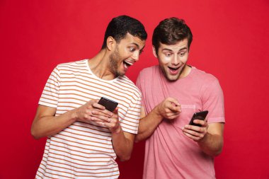 Cep telefonunda oyun izole kırmızı arka plan üzerinde duran iki neşeli genç adam