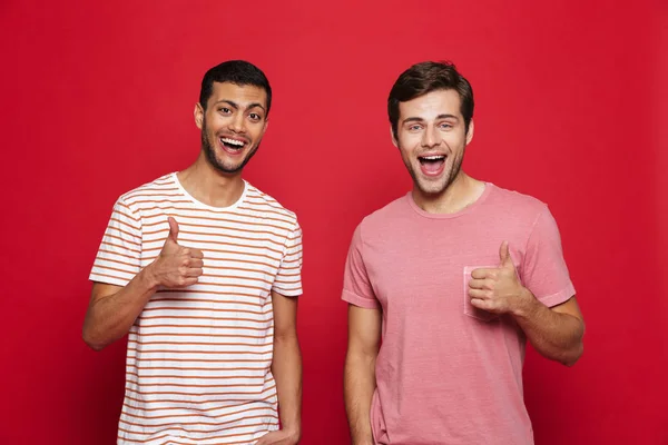 Two Cheerful Young Men Standing Isolated Red Background Giving Thumbs — Stock Photo, Image