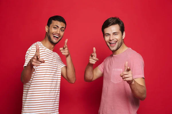 Dois Jovens Alegres Isolados Sobre Fundo Vermelho Apontando Para Câmera — Fotografia de Stock