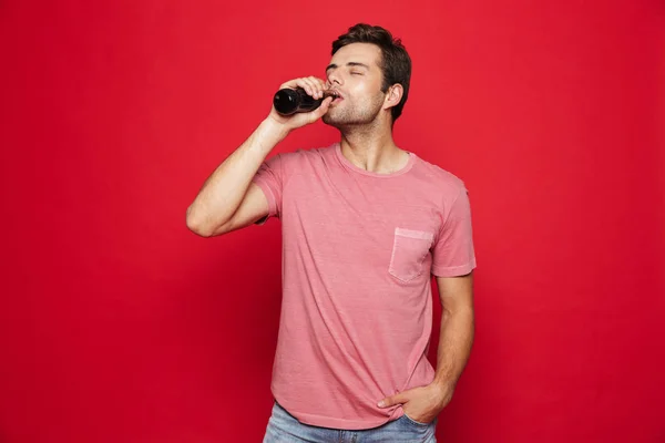 Portrait Delighted Young Man Drinking Soda Bottle Isolated Red Background — Stock Photo, Image