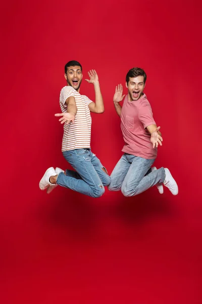 Dois Homens Alegres Amigos Pulando Isolados Sobre Fundo Vermelho — Fotografia de Stock