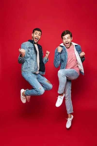 Longitud Completa Dos Jóvenes Alegres Saltando Aislados Sobre Fondo Rojo — Foto de Stock