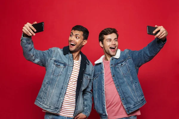Two Cheerful Young Men Standing Isolated Red Background Taking Selfie — Stock Photo, Image