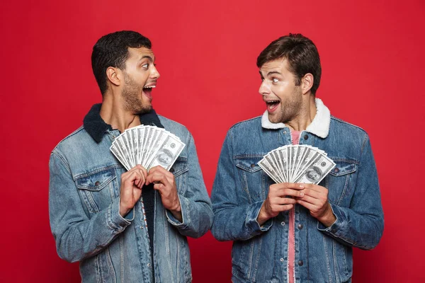 Twee Vrolijke Jonge Mannen Rode Achtergrond Geïsoleerd Staande Houden Geld — Stockfoto