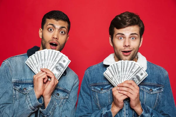 Twee Vrolijke Jonge Mannen Rode Achtergrond Geïsoleerd Staande Houden Geld — Stockfoto