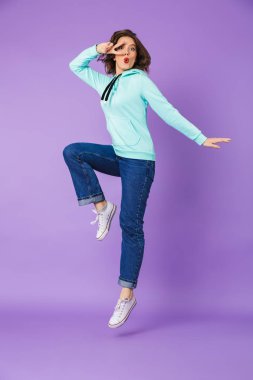 Heyecanlı bir güzel genç kadının poz görüntü gösteren barış atlama mor arka plan duvardan izole.