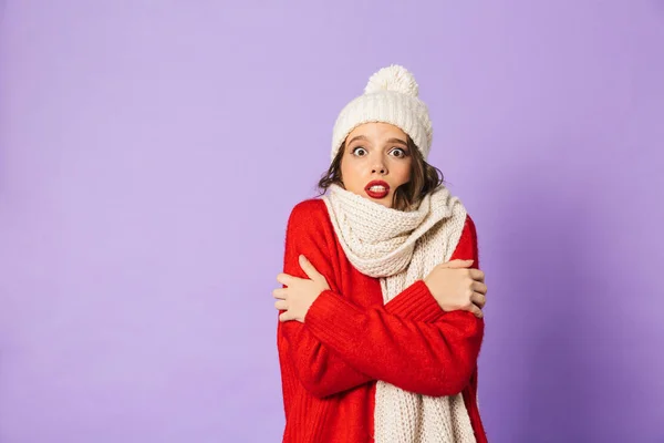 一个年轻的冷冻妇女的肖像穿着冬天的帽子和围巾查出在紫色背景 — 图库照片