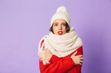 Kış şapka ve atkı mor arka plan üzerinde izole giyen genç bir donmuş kadın portresi.