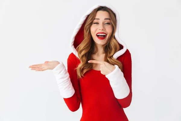快乐女孩20多岁的图片 穿着圣诞红色礼服 指着版权空间在手掌 而站在孤立的白色背景 — 图库照片