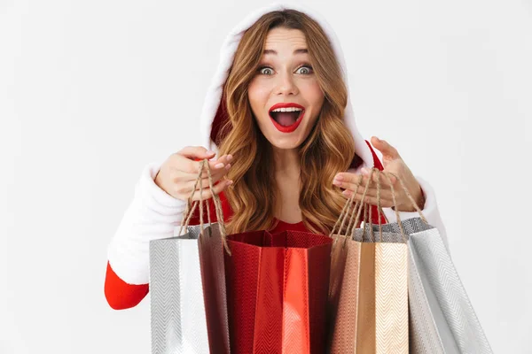 美丽的妇女20多岁的肖像穿着圣诞老人红色服装微笑 拿着五颜六色的纸购物袋与购买查出在白色背景 — 图库照片