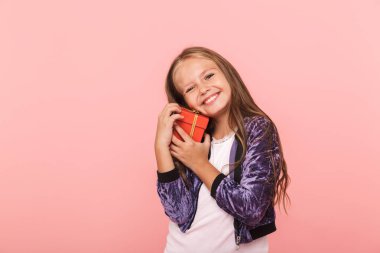 Küçük kız pembe arka plan üzerinde izole ayakta mevcut kutusu sarılma gülümseyen