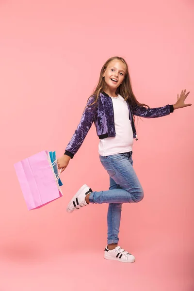 Весела Маленька Дівчинка Ізольована Рожевому Тлі Несучи Сумки Покупок Ходьба — стокове фото
