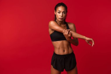 Siyah spor giyim izole kırmızı arka plan üzerinde vücudu germe jimnastik Afrikalı-Amerikalı kadın portresi