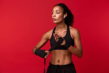 Siyah spor spor bandaj izole kırmızı arka plan üzerinde ellerini giyen sportif Afrikalı-Amerikalı kadın görüntüsünü
