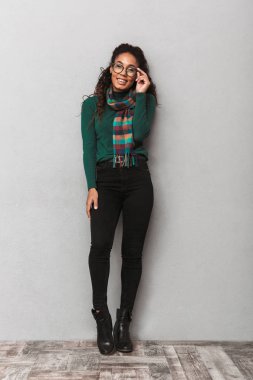 Mutlu bir Afrikalı kadın kazak ayakta gri duvar arka plan üzerinde giyen tam uzunlukta