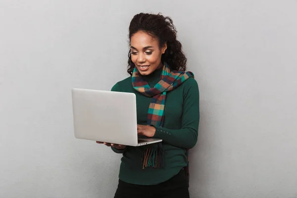 愉快的非洲妇女戴围巾站在灰色的背景隔离 拿着笔记本电脑 — 图库照片