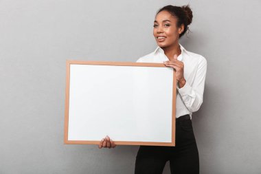 Holding boş yönetim kurulu gri arka plan üzerinde kalan forması giyen çekici genç Afrika iş kadın izole