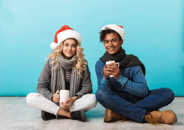 Lyckliga Multiracial Teenage Paret Sitter Isolerade Över Blå Bakgrund Bär — Stockfoto