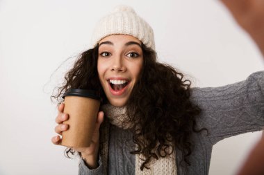 Bir paket servisi olan restoran kahve fincanı tutan bir selfie alarak beyaz arka plan üzerinde izole ayakta kış eşarp neşeli genç kadın