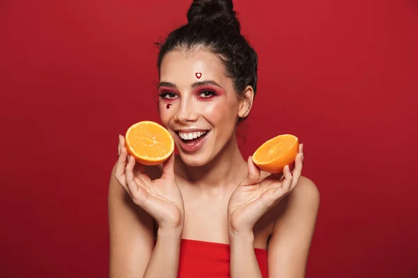 美容化粧赤い背景 ポーズ 持株のスライス オレンジを分離立って魅力的な若い女性の肖像 — ストック写真