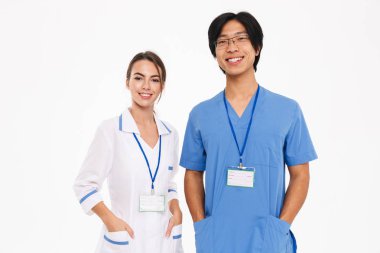 Mutlu doktorlar çift giyen üniforma ayakta beyaz arka plan üzerinde izole