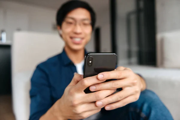 Feliz Asiático Homem Sentado Sofá Casa Usando Fones Ouvido Usando — Fotografia de Stock